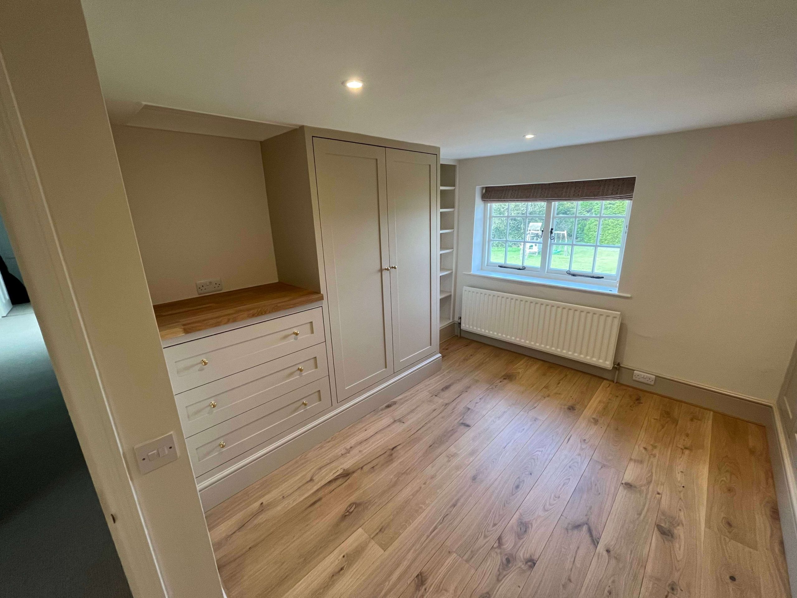 Home Built-in bedroom storage with painted wardrobe, oak-topped drawers and open shelving beside a window