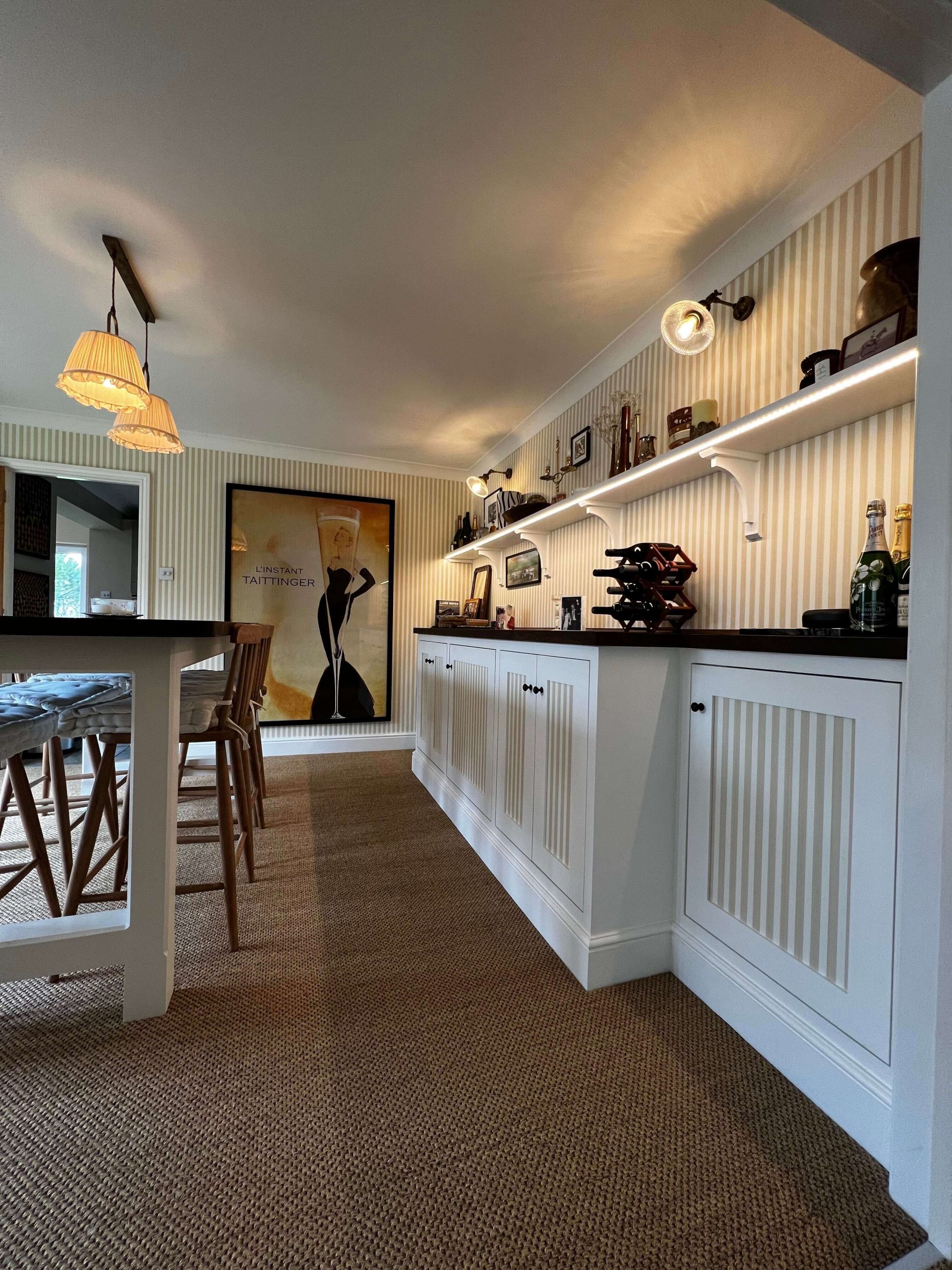 Home Built-in bar cabinetry with painted panelled doors, dark timber top and a lit display shelf above