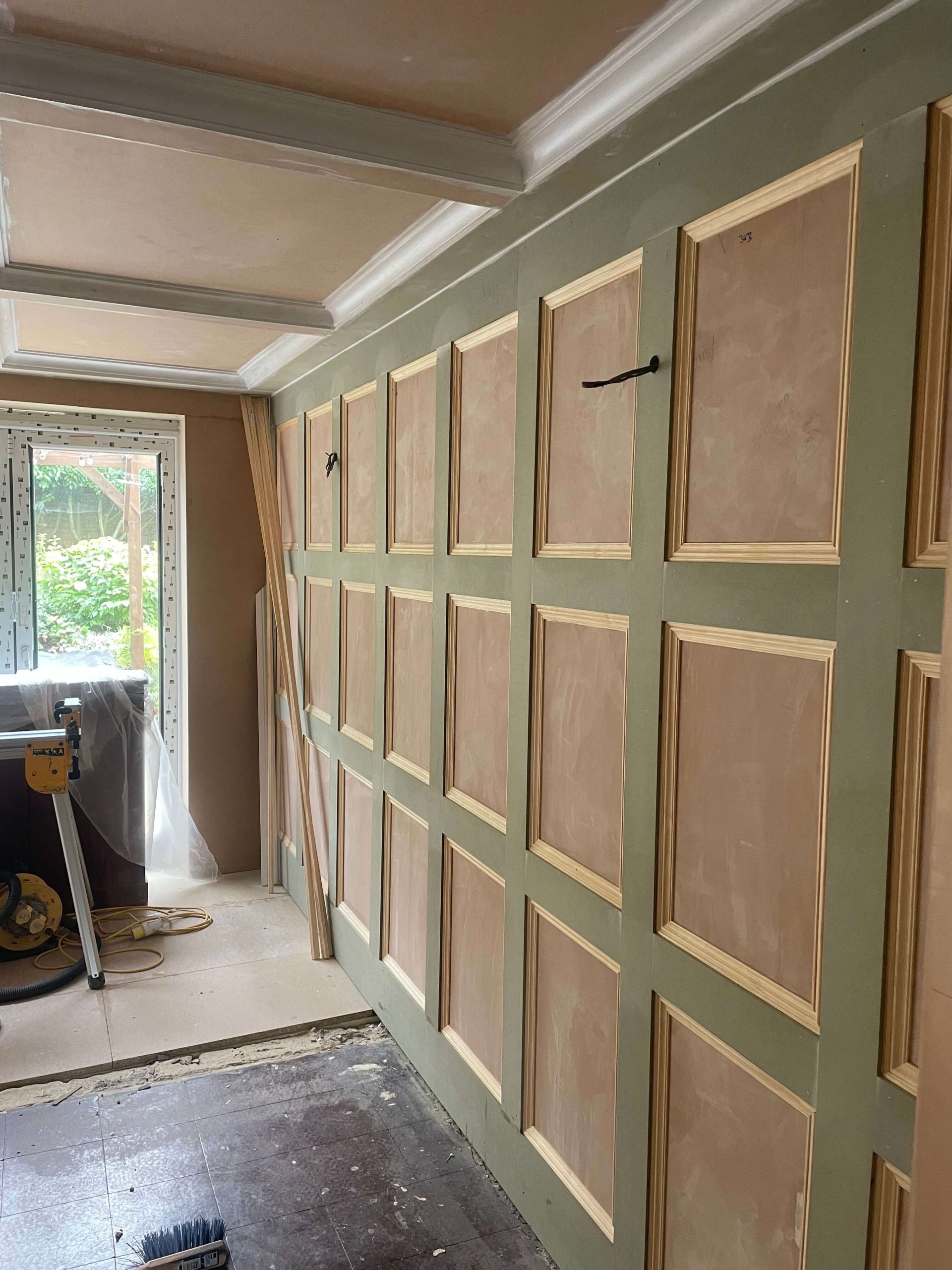 Services Wall panelling part-built, with primed panels and moulded beading fixed to a green painted wall