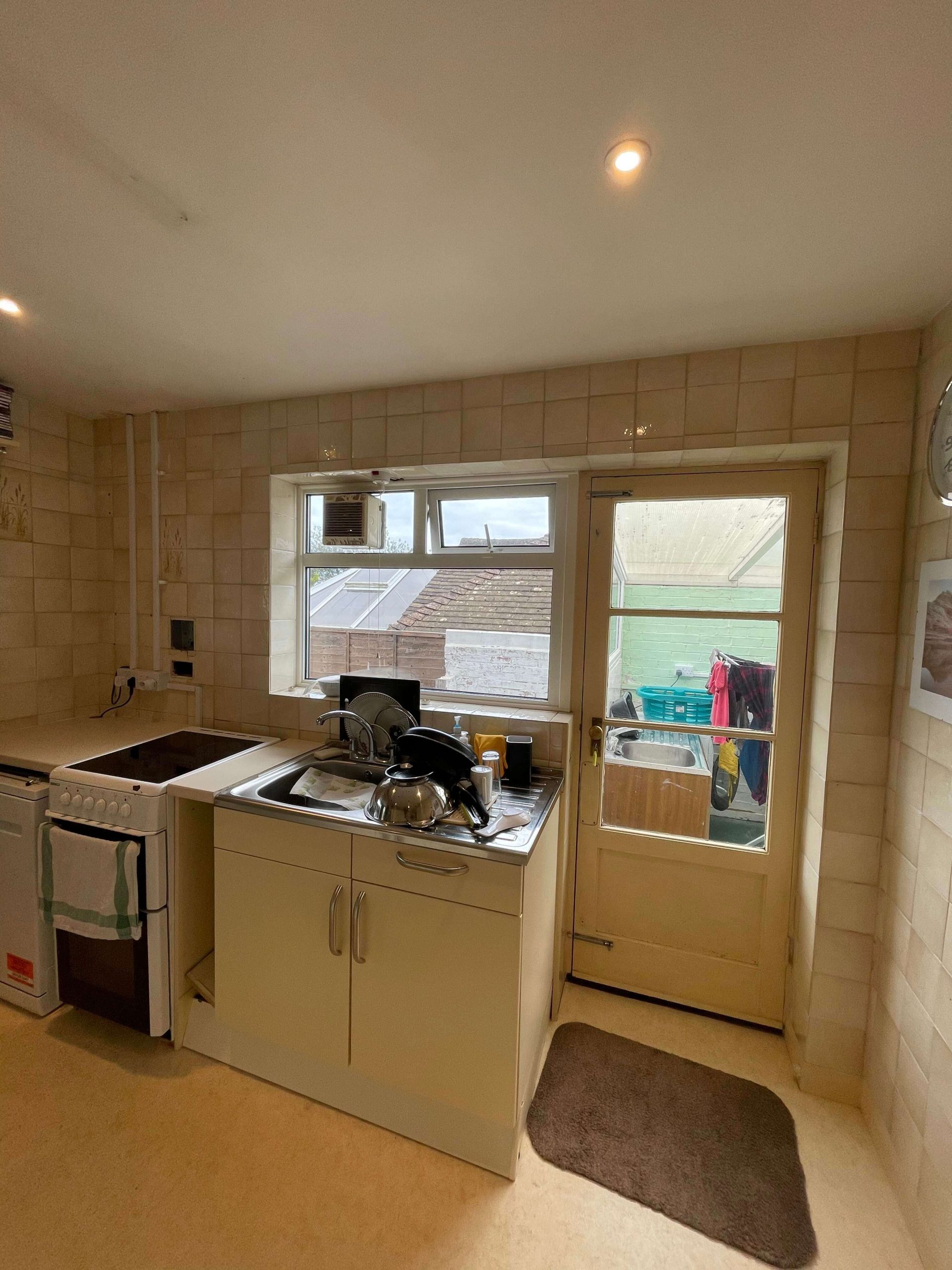 Home Kitchen before refurbishment, with dated wall tiling and original fitted units