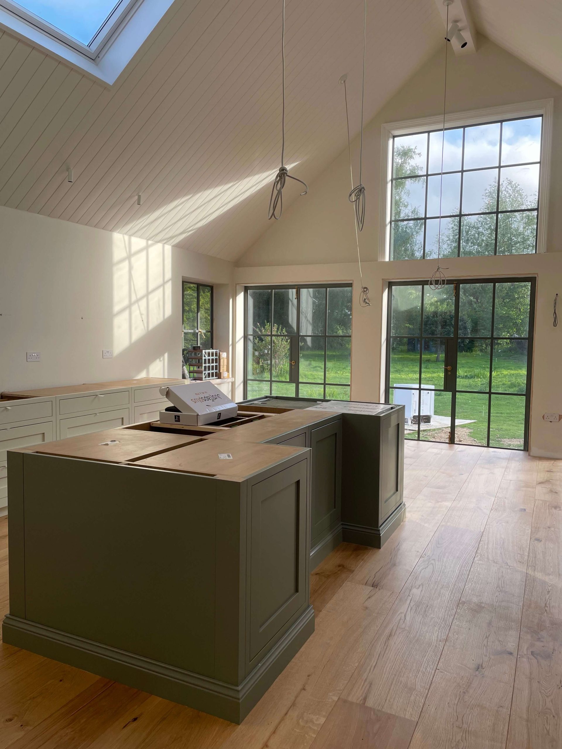 Services Open-plan kitchen with vaulted panelled ceiling, steel-framed garden doors and a green painted island
